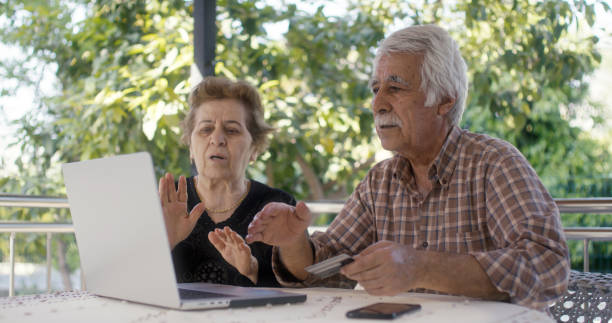 istock Senior couple having problem with fraud while online shopping with credit cart using laptop computer 2148898983