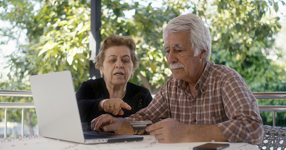 Senior couple having problem with fraud while online shopping with credit cart using laptop computer