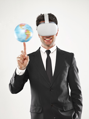 Businessman wearing virtual reality glasses and twisting a globe  on his finger