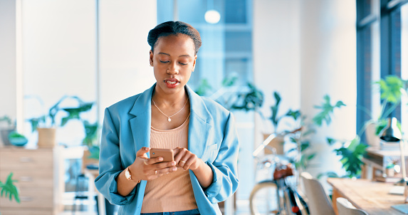 African woman, phone and texting in office for contact, networking and communication at startup. Girl, person or employee on cellphone for notification, typing and reading at creative media agency