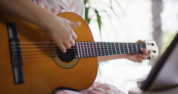 istock Adolescence girl playing guitar at home 2148902581