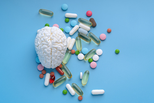 Brain surrounded by pills on blue background top view