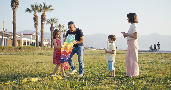 Father and children playing with a kite at seaside