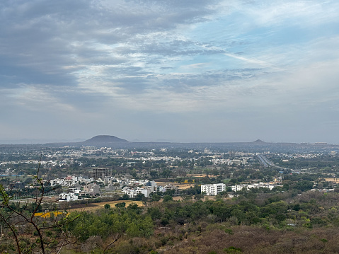 A city view with a cloudy sky and mountains in the background. The city is full of buildings and houses at Ralamandal, Indore, India