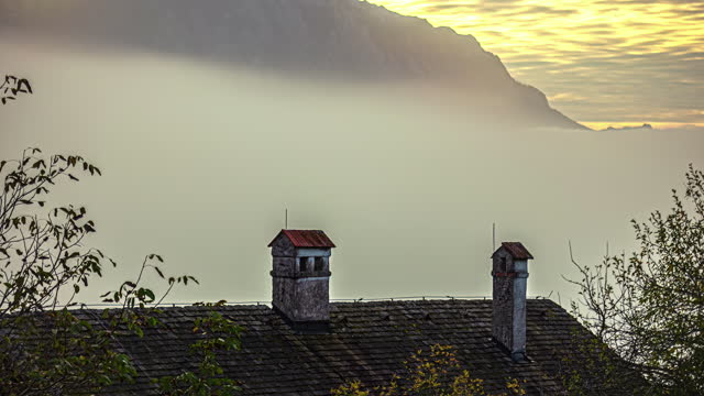 Fog gracefully envelops the rooftop of an ancient medieval house in time lapse