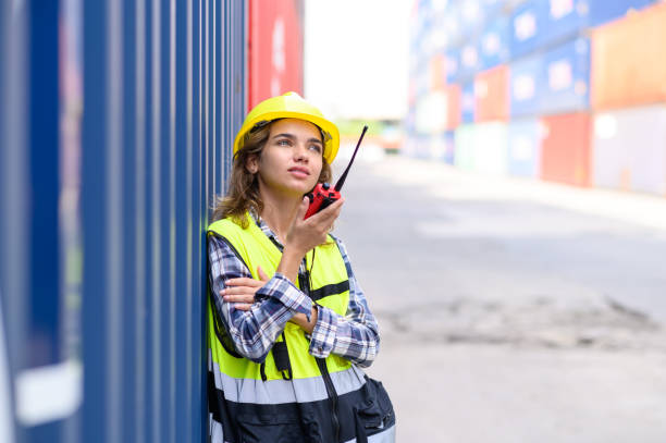 istock container operators women wearing helmets and safety vests control via walkie-talkie workers in container yards. Cargo Ship Import Export Factory Logistic.. 2148909224