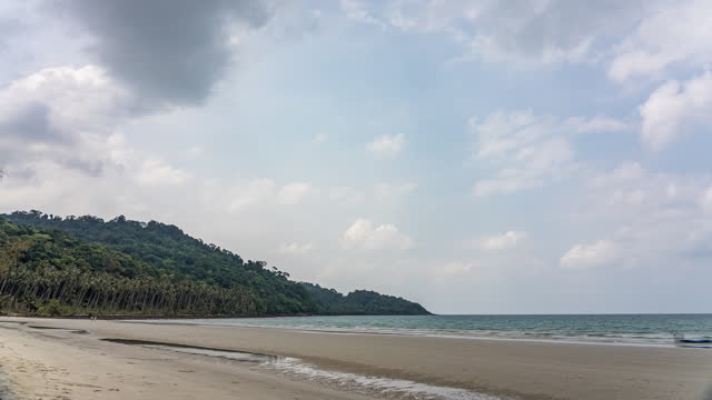 Timelapse of moving clouds against blue sky above beautiful white sand beach at Koh Kood, Trat, Thailand