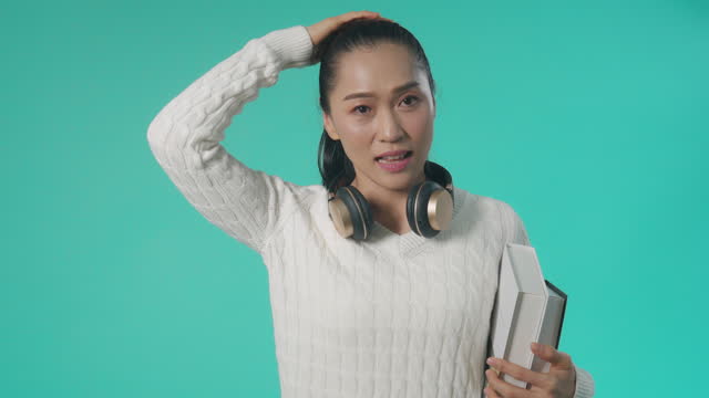 Playful happy Asian woman with Books , headphones and dancing .