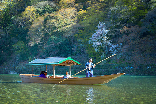 Kyoto, Japan - March 29 2023: Unidentified people ride a boat that sails in Katsura river  in Arashiyama district