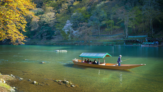 Kyoto, Japan - March 29 2023: Unidentified people ride a boat that sails in Katsura river  in Arashiyama district