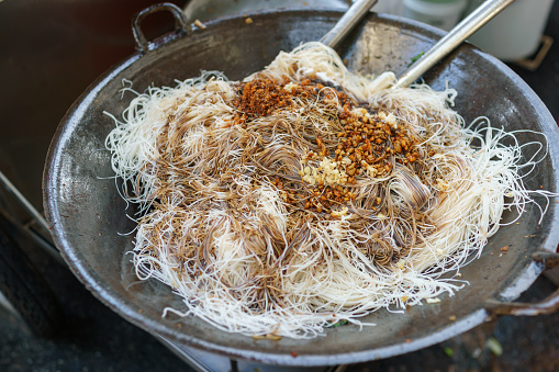High angle view of a hawker cooking rice noodles at street stall, a popular Penang street food