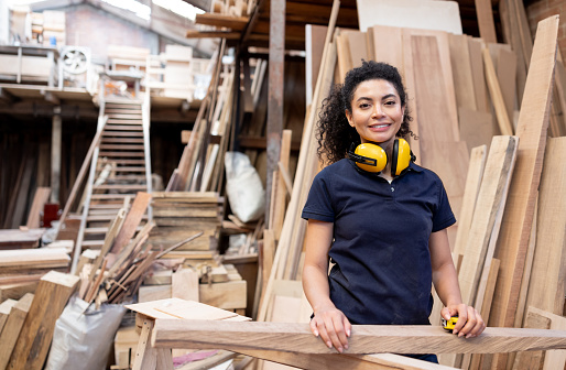 Latin American woman working at a wood factory and looking at the camera smiling