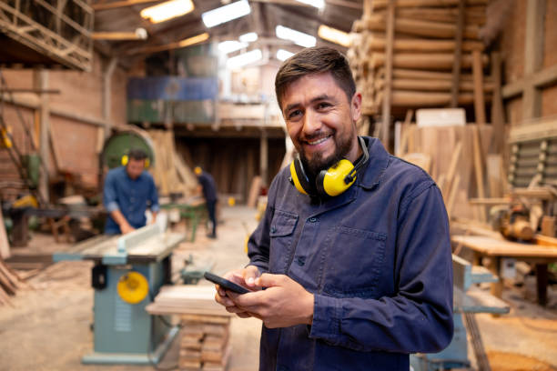 istock Man working at a timber factory and using his cell phone while taking a break 2148914832
