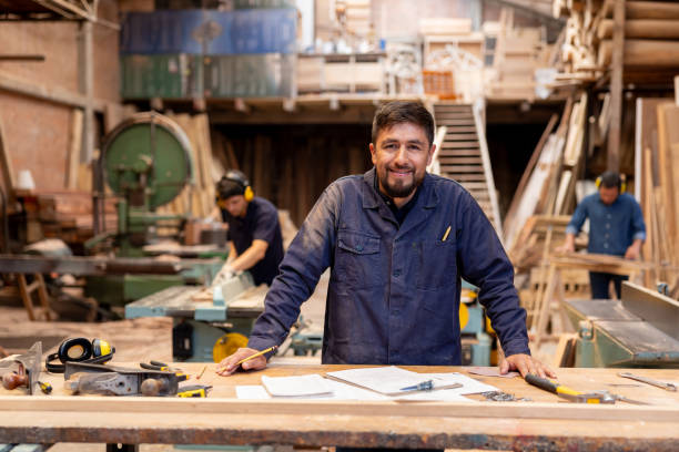 Man working at a wood factory and looking at the camera smiling Portrait of a Latin American man working at a wood factory and looking at the camera smiling working class stock pictures, royalty-free photos & images