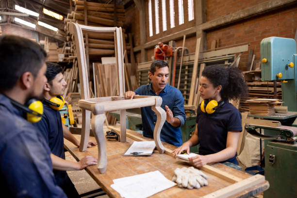 Foreman talking to a group of employees while manufacturing a chair
