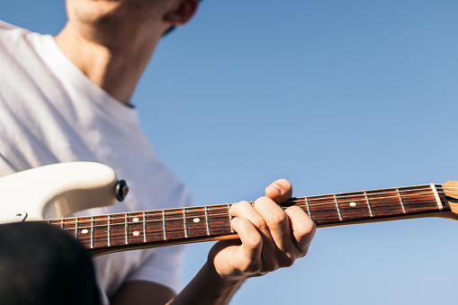 man playing electric guitar outdoors. close-up