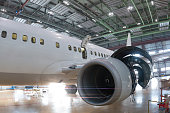 White passenger jet plane in the aviation hangar. Checking mechanical systems for flight operations