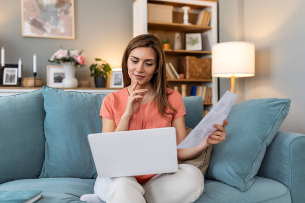 istock Nice beautiful woman work on laptop notebook sit down on the sofa at home - check on analytics - technology woman concept for alternative office freelance 2148920134