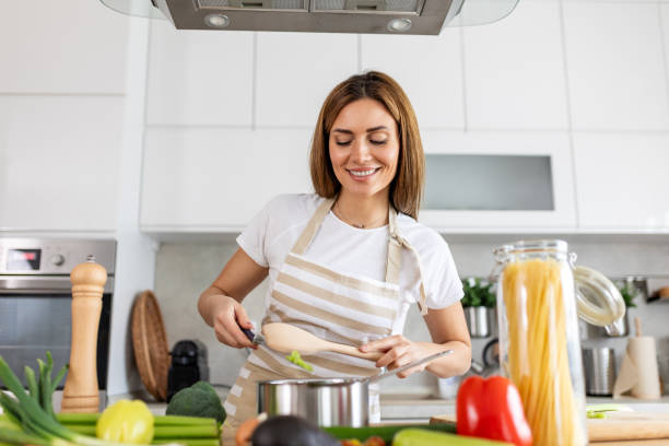 istock Joyful Young Lady Cooking and Sampling Dinner in a Pot, Present in a Contemporary Home Kitchen. Homemaker Preparing Nutritious Meal with a Smile. Domestic Life and Nourishment. Healthy Eating. 2148920193