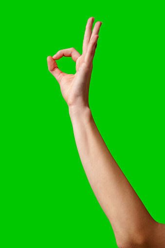 A solitary hand is raised against a bright green background, fingers curled into a circle while the thumb and index finger touch to form the universally recognized okay sign, suggesting approval or that everything is fine.