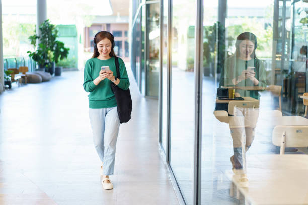 istock Happy beautiful Asian young woman using smartphone while walking outside. 2148923266