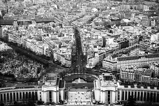 View, in black and white, over central Paris, with the Eiffel tower in the distance, and La Defense business district beyond.