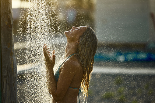 Happy woman enjoying while taking a shower in nature.