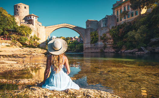 Woman in white dress looking at Old bridge in Town of Mostar- Bosnia Herzegovina