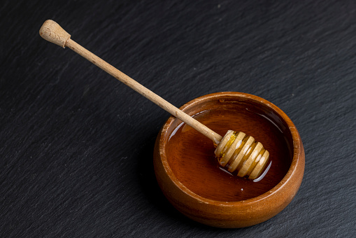 fresh flowing honey in a wooden bowl, natural bee honey in a round wooden plate