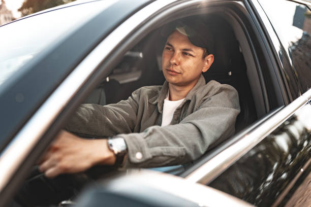 istock Young smiling man sitting in a car with open window 2148927718