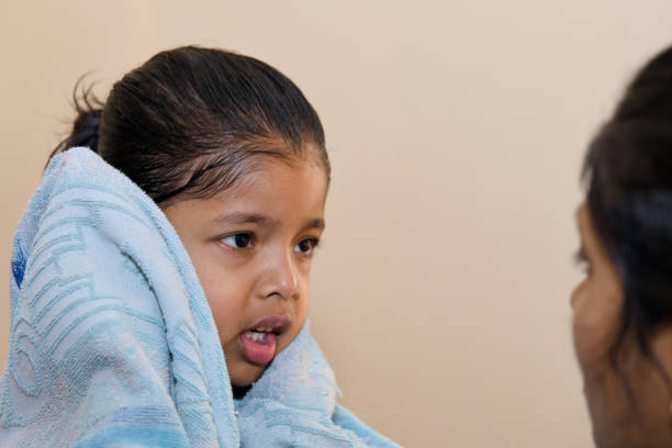 A nurturing mother lovingly wraps her child in a fluffy towel after a playful bath. Perfect for illustrating parental care