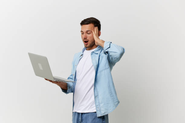 istock Excited shocked tanned handsome man in casual basic t-shirt have operation problems with laptop touch temple posing isolated on over white background. Copy space Mockup. Electronics repair IT concept 2148930541