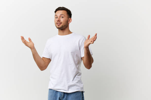 istock Happy cheerful tanned handsome man in basic t-shirt spread hands can't make decision posing isolated on over white studio background. Copy space Banner Mockup. People emotions Lifestyle concept 2148930707