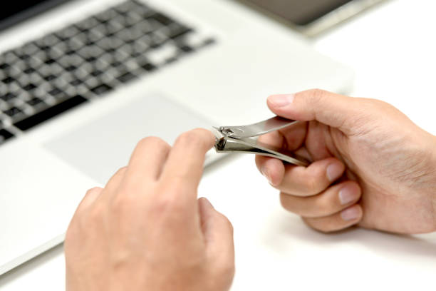 A man's hand cutting his nails with a nail clipper
