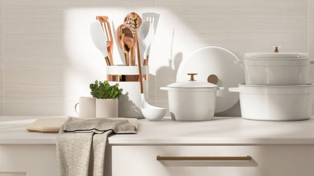 istock Beige kitchen table counter, cutting board, pots on countertop in sunlight on wood pattern tile wall in background 2148931409