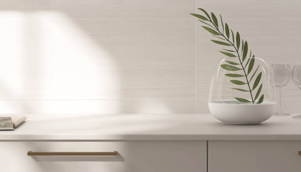 istock Beige kitchen table counter, plant twig on countertop in sunlight on wood pattern tile wall in background 2148931424