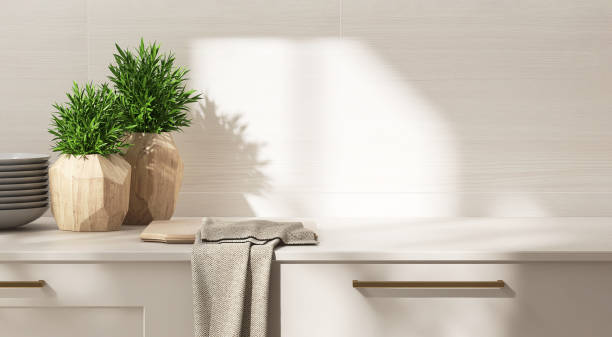 Beige kitchen table counter, plant, cutting board on countertop in sunlight on wood pattern tile wall in background