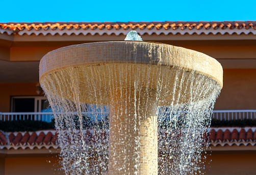 Water fountain in front of house with blue sky in the background. Splashing water in the summer