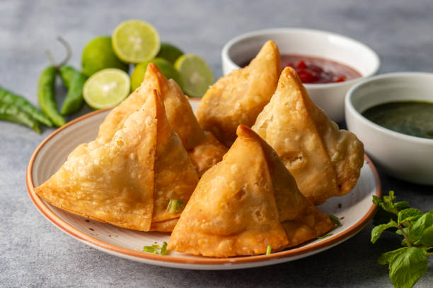 istock selective focus Samosa, Spiced potato-filled pastry, crispy, Savory, popular Indian snack with tomato and mint chutney. 2148933057
