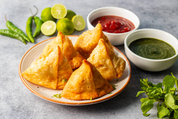 istock selective focus Samosa, Spiced potato-filled pastry, crispy, Savory, popular Indian snack with tomato and mint chutney. 2148933060