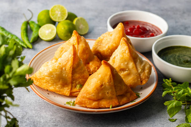istock selective focus Samosa, Spiced potato-filled pastry, crispy, Savory, popular Indian snack with tomato and mint chutney. 2148933065