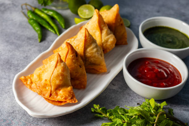 istock selective focus Samosa, Spiced potato-filled pastry, crispy, Savory, popular Indian snack with tomato and mint chutney. 2148933104