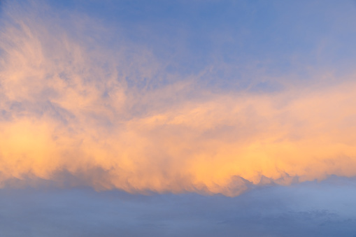 A serene sunset sky, awash with vibrant shades of orange and blue, creates a captivating backdrop, ideal for sky replacement or as a standalone piece in creative projects