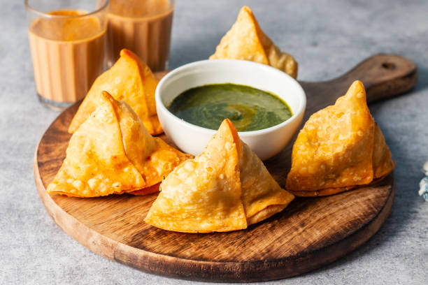 istock selective focus Samosa, Spiced potato-filled pastry, crispy, Savory, popular Indian snack serve with tomato and mint chutney and teas. 2148933149