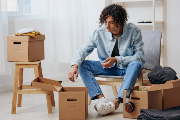 istock guy with curly hair sitting on a chair with boxes interior moving interior 2148933765