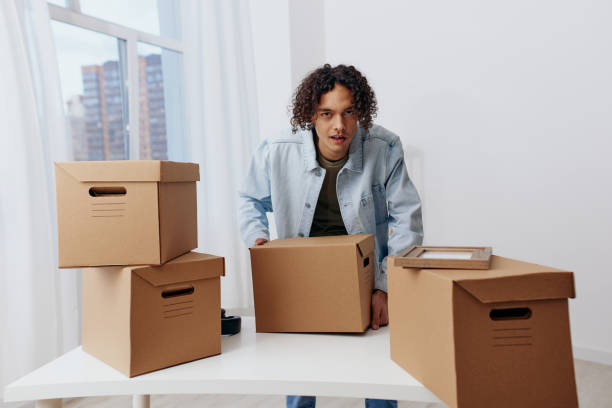 istock handsome guy unpacking things from boxes in the room interior 2148933807