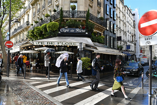 Paris, France-04 16 2024: People crossing street in front of the famous Parisian Café de Flore in the Saint-Germain-des-Prés district, France.