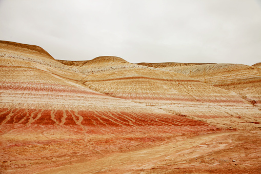 Unique geological feature known as tiger-striped mountains, showcasing layers of sedimentary rock in warm tones that resemble the stripes of a tiger.