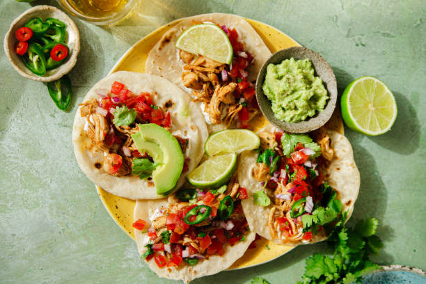 istock Homemade Mexican Tacos served with lime and avocado over green table 2148934521