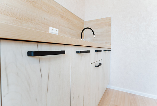 Cabinetry with white wood stain, black handles, and a sink fixture
